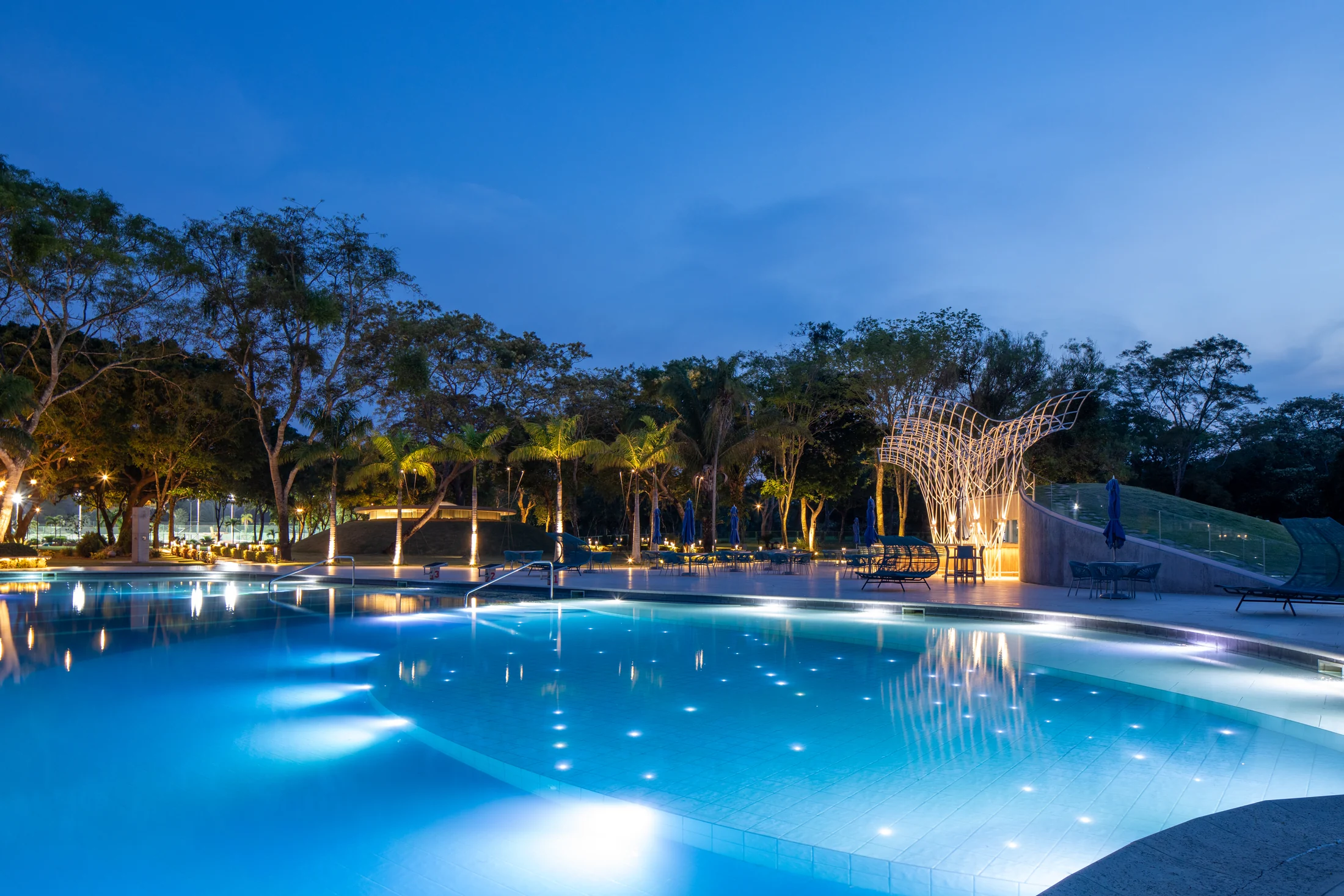 Piscina iluminada del Village Country Club al atardecer